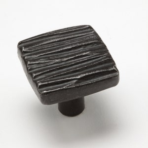 May include: A square, dark bronze cabinet knob with a textured, ridged surface. The knob has a short, cylindrical base. The hardware is designed for use on drawers, cabinets, or other furniture pieces. The finish is a dark, matte bronze.