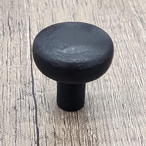 May include: Black round cabinet knob with a textured finish.