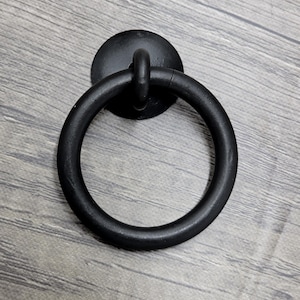 May include: Black metal ring door knocker with a round base and a circular handle.