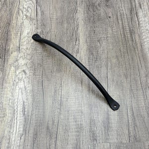 May include: Black metal handle with rounded ends. The handle is curved and has a smooth finish.