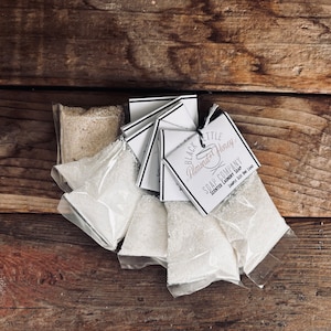 May include: Five small white bags of laundry soap with a black and white label that reads "Black Kettle Almond Honey Soap Company Scented Laundry Soap Sample Size One Load"