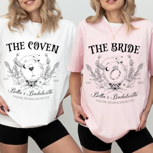 May include: Two t-shirts, one white and one pink, with black text and graphic designs. The white shirt says "THE COVEN" and the pink shirt says "THE BRIDE". Both shirts have the text "Bella's Bachelorette" and "SALEM, MASSACHUSETTS".