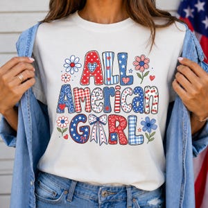 May include: White t-shirt with the text "ALL AMERICAN GIRL" in red, white, and blue letters. The letters have various patterns, including polka dots, stripes, and gingham. Floral and star accents surround the text.
