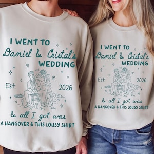 May include: Two beige sweatshirts with matching text and graphics. The text reads "I went to Daniel & Cristal's Wedding" with the year "2026" and the phrase "& all I got was A HANGOVER & THIS LOUSY SHIRT". A line drawing of a couple is also present.