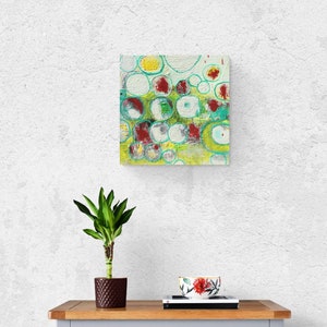 May include: Abstract painting with a green, yellow, white, and red color scheme. The painting features a pattern of overlapping circles with a textured surface.