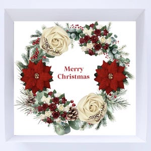 以下が含まれることがあります： 白い背景に額装されたクリスマスリース。リースは、クリーム色のバラ、赤いポインセチア、小さな赤いベリーが特徴です。「メリークリスマス」という言葉がリースの中心にあります。