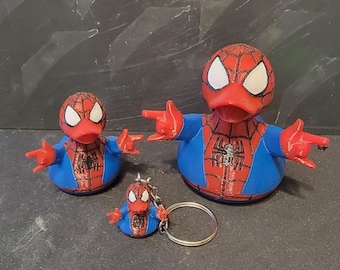 May include: Three Spider-Man-themed rubber ducks in different sizes. The ducks are red, blue, and white, with the Spider-Man mask design. One is a keychain. The ducks have outstretched arms.