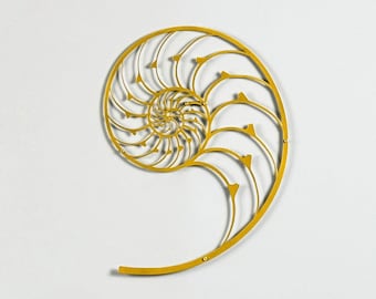 Può includere: Una scultura da parete in metallo dorato a forma di conchiglia di nautilus. La scultura è appesa a una parete bianca sopra un tavolo di legno con un vaso di gigli bianchi e un libro.