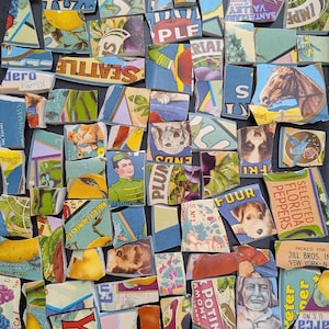 May include: A collection of assorted ceramic shards featuring vintage-style graphic prints, including illustrations of a horse, dogs, a person in a uniform, fruit, and text fragments like Seattle, Florida Peppers, and Jill Bros. New York.