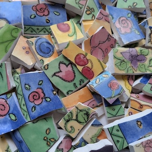 May include: A collection of ceramic mosaic tiles featuring hand-painted floral and fruit motifs in shades of blue, green, yellow, and pink. Each piece displays distinct patterns including roses, tulips, and cherries with black outlines.