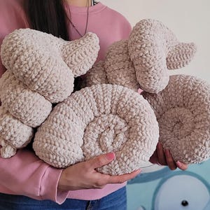 Op de afbeelding: Vier beige gebreide kussens in de vorm van een schelp. De kussens zijn zacht en pluche en zouden perfect zijn om een vleugje whimsy toe te voegen aan elke kamer.