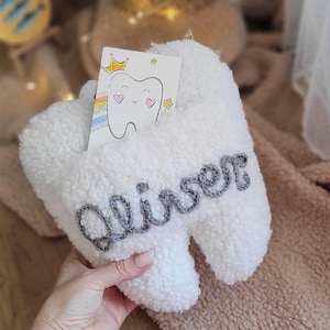 May include: White plush tooth-shaped box with a gray embroidered name "Aliser" on it. A small card with a cartoon tooth and a rainbow is tucked inside the box.