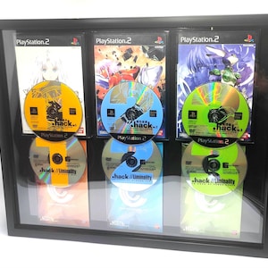 May include: A black framed display case with six video game discs. The discs are arranged in three rows of two. The discs are all silver with a rainbow holographic effect. The discs have the text "hack" and "hack//Liminality" on them. The display case has the text "PlayStation 2" on it.