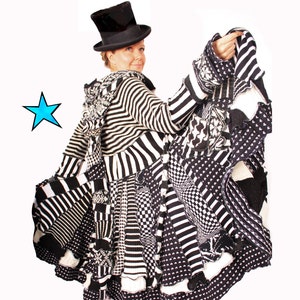 Może przedstawiać: Czarno-biały, prążkowany kardigan z kapturem i patchworkowym wzorem. Kardigan jest wykonany z różnych dzianin i ma falbaniasty dół. Modelka ma na sobie czarny cylinder.