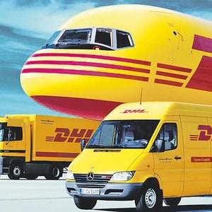 May include: A yellow DHL delivery truck with the DHL logo on the side. The truck is parked in front of a yellow DHL airplane with the DHL logo on the side.