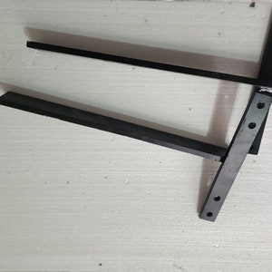 May include: Two black metal shelf brackets with multiple holes for mounting.
