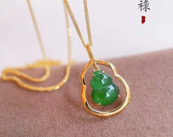 May include: A gold chain necklace with a green jade gourd pendant. The pendant is set in a gold frame and has a delicate design. The necklace is on a brown background with the Chinese characters for "good fortune" written in red.