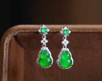 May include: A pair of green jade earrings with diamond accents. The earrings are shaped like gourds and are hanging from a silver post.