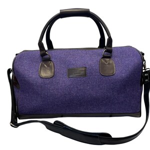 May include: A purple felt travel bag with black leather handles and a shoulder strap. The bag has a small leather patch with the text "The Original Travel Company" on the front.