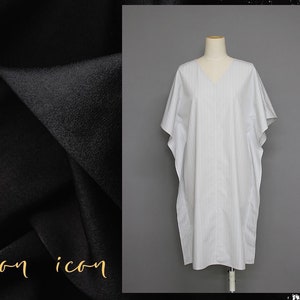 May include: A white and gray striped kaftan with a V-neckline. The kaftan is made of a lightweight fabric and has a relaxed fit.