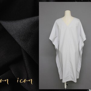 May include: A white and gray striped kaftan-style dress with a V-neckline. The dress is on a white mannequin.