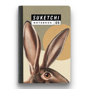 Puede incluir: Una libreta marrón y beige con una ilustración de conejo en la portada. La libreta tiene el texto "SUKETCHI NOTEBOOK 09" impreso en la parte delantera.