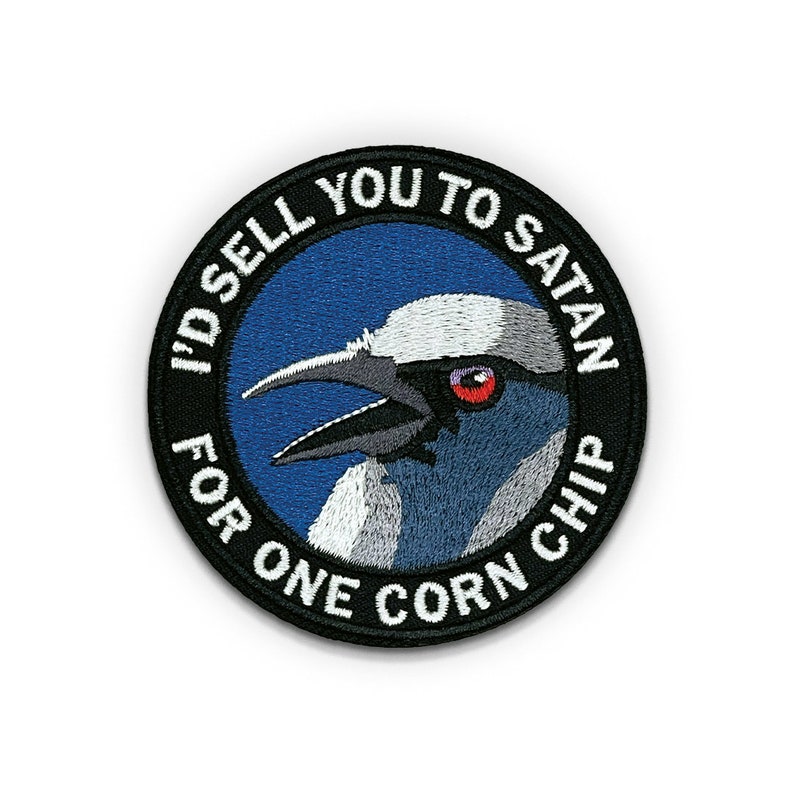Może przedstawiać: Naszywka haftowana w kolorze czarnym i białym z niebieskim tłem. Naszywka przedstawia ptaka z czerwonym okiem i tekstem "I'd sell you to Satan for one corn chip".