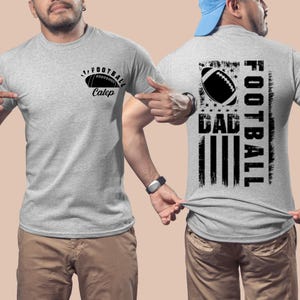 May include: A gray t-shirt with a black football graphic and the text "Football Caleb" on the front. The back of the shirt features a black and white American flag design with the text "Football Dad" in a vertical orientation.
