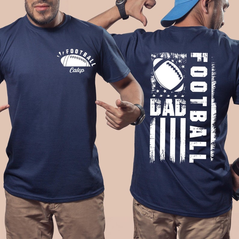 May include: A navy blue t-shirt with a white football graphic and the text "Football Dad" on the back. The back graphic also features a white American flag design.