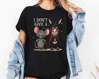 May include: Black t-shirt featuring a cartoon mouse and donkey with the text "I DON'T GIVE A". The mouse is gray with pink ears and a star on its chest. The donkey is black with a pink halter and lead.
