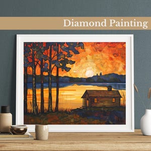 May include: Diamond painting depicting a cabin in the woods at sunset. The cabin is brown with a wooden door and windows. The trees are silhouetted against the orange and yellow sky. The water is a dark blue.