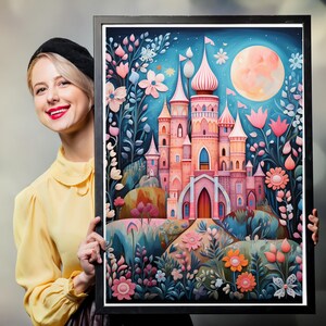 May include: A framed vertical art print featuring a pink castle with multiple towers and pointed roofs, set against a dark blue night sky with a large pale moon. The scene is surrounded by stylized pink and orange flowers and foliage.