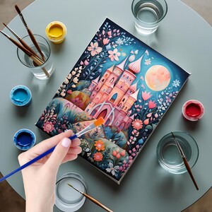 May include: A rectangular canvas featuring a colorful illustration of a pink castle surrounded by stylized flowers and a large moon against a dark blue sky. Several paintbrushes, small containers of paint, and glasses of water are arranged nearby.