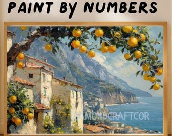 May include: A paint by numbers kit featuring a coastal landscape with white buildings, a blue sea, and a foreground lemon tree with bright yellow fruit. The text PAINT BY NUMBERS is printed at the top, and DIAMONDCRAFTCOR is visible on the painting.