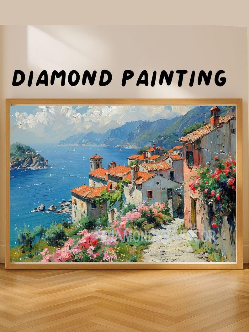May include: A framed diamond painting featuring a coastal landscape with Mediterranean-style houses, red roofs, and pink flowers along a stone path overlooking a blue sea and mountains. The text DIAMOND PAINTING is printed above the artwork.