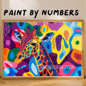 Puede incluir: Un kit de pintura por números con una ilustración de jirafa multicolor en un marco de madera. La obra muestra formas abstractas audaces en amarillo, azul, morado y naranja, con el texto PAINT BY NUMBERS visible sobre el marco.