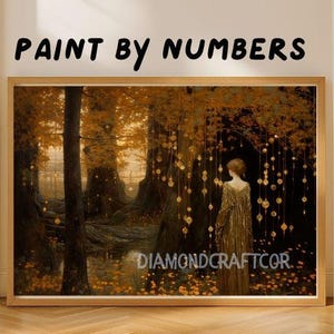 Puede incluir: Un kit de pintura por n&uacute;meros enmarcado que presenta una serena escena de bosque con una figura con un vestido dorado. La obra de arte tiene una c&aacute;lida paleta de colores dorados, marrones y verdes. El texto "PAINT BY NUMBERS" est&aacute; en la parte superior y "DIAMONDCRAFTCOR" en la inferior.