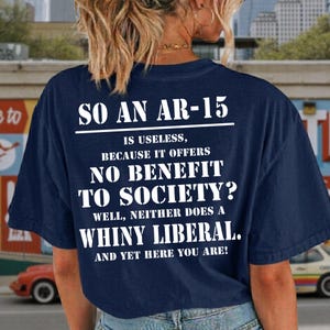 以下が含まれることがあります： 白文字のネイビーブルーTシャツ。テキストは「SO AN AR-15 IS USELESS, BECAUSE IT OFFERS NO BENEFIT TO SOCIETY? WELL, NEITHER DOES A WHINY LIBERAL. AND YET HERE YOU ARE!」と書かれています。