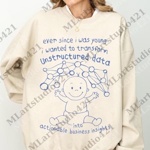 Puede incluir: Sudadera beige con un gráfico azul de un bebé y un diagrama de red. El texto dice: "ever since I was young; I wanted to transform Unstructured data into actionable business insights."