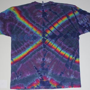 May include: A tie-dye t-shirt with a rainbow pattern on a dark blue background. The shirt has a relaxed fit and short sleeves.