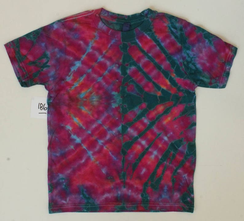 May include: A tie-dye t-shirt with a green, blue, pink, and orange colour scheme. The shirt has a diagonal pattern with a darker green section on the right side.