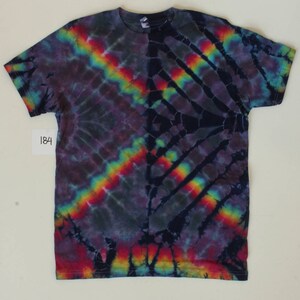 Może przedstawiać: Koszulka tie-dye z ciemnoniebieskim, fioletowym i czarnym tłem. Koszulka ma wz&oacute;r tęczy w kolorach czerwonym, pomarańczowym, ż&oacute;łtym, zielonym, niebieskim i fioletowym. Koszulka ma metkę z numerem 184.
