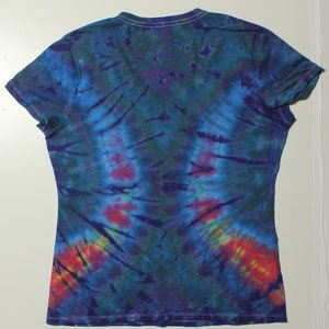 May include: A tie-dye V-neck t-shirt in shades of blue, green, purple, and red. The shirt has short sleeves and a white neckline. The tie-dye pattern radiates from the center, creating a unique design.