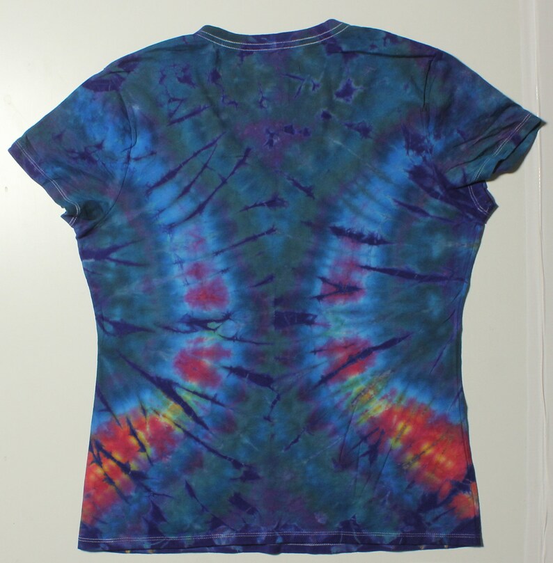 May include: A tie-dye V-neck t-shirt in shades of blue, green, purple, and red. The shirt has short sleeves and a white neckline. The tie-dye pattern radiates from the center, creating a unique design.