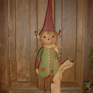 May include: A handmade rag doll elf with a red hat, green and red clothing, and a scroll in its hand. The elf is standing on a wooden door.