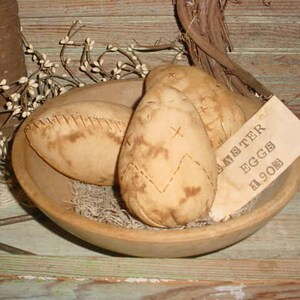 May include: Three brown fabric Easter eggs in a wooden bowl with a white tag that says "Easter Eggs $1.90s".
