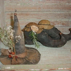 May include: A witch's hat with a brown brim and a black pointed crown, decorated with burlap and dried flowers.  Two black and brown elf shoes with pointed toes are also pictured.