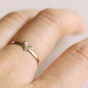 May include: A silver ring with a V-shaped design. The ring is worn on a finger.