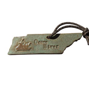 May include: A green ceramic ornament shaped like the state of Tennessee with the words "Ocoee River" and a stylized image of a canoe with people paddling.
