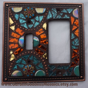 Pu&ograve; includere: Una placca per interruttore della luce color rame con un design a mosaico con piastrelle di vetro turchese, arancio e oro. Il design del mosaico &egrave; intricato e presenta forme geometriche e motivi.